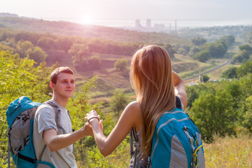 Come with Me Girlfriend and Boyfriend Couple with Backpacks on Green Forest Background Holding Hands Leading Smiling rising Sun on Background