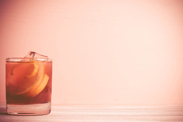 Old fashioned cocktail on the wooden background. Toned image. Vintage style.