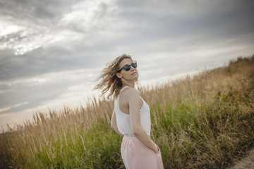 Fototapeta na wymiar beautiful young woman posing on a meadow. Summer fashion photo. Lifestyle