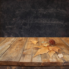 autumn background of fallen leaves over wooden table and blackboard backgrond with room for text