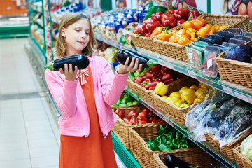 Girl chooses eggplants in supermarket