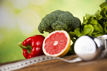 Health and fitness concept with dumbbells, measure tape and fresh fruit 