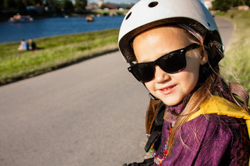 Fototapeta na wymiar Cute little girl wearing in roller skates protection outdoors