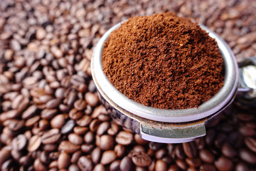 Freshly ground coffee beans in a metal filter on coffee beans background 
