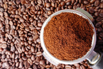 Freshly ground coffee beans in a metal filter on coffee beans background 