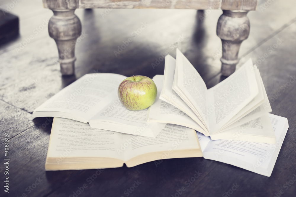 Poster apple and four open books on a floor
