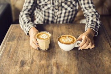 Girl hands with two cups of coffee on a wooden table