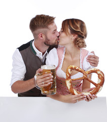 Bayrisches Paar in Tracht mit Bier und Brezel über weißer Wand isoliert