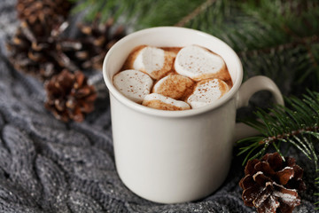 White cup of fresh hot cocoa or hot chocolate with marshmallows on knitted background, copy space for text