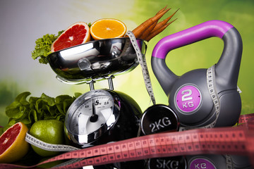 Health and fitness concept with dumbbells, measure tape and fresh fruit 