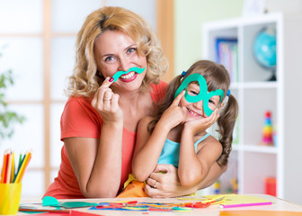 Kid with mother have a fun cutting out scissors paper in
