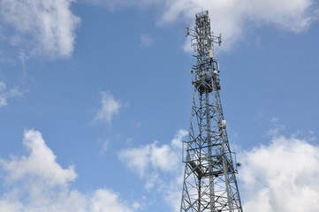 Telecommunication tower against cloudy sky