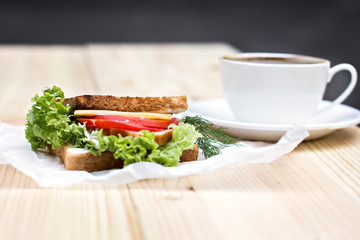 Sandwich and cup of black coffee on the table