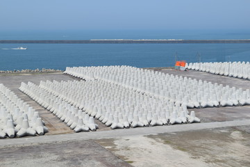 海岸侵食防止用の消波ブロック／山形県の庄内浜で撮影した「消波ブロック」の写真です。消波ブロックは、海岸や河川などの護岸を目的に設置するコンクリートブロックです。海岸沿いに多数のブロックをかみ合わせて並べることで、波のエネルギーを減衰・消散させる事が可能です。また、このブロックにより、水中に複雑で多様な生物生息空間を提供し、円滑な生態系が形成され豊かな水域環境を創り出しています。