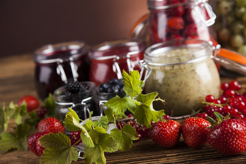 Glass of mixed berry jam with strawberries, bilberries, red currants and blackberries