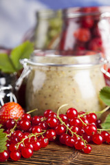 Berries jam in glass jar and wood background