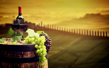 Fototapeta na wymiar Red wine bottle and wine glass on wodden barrel. Beautiful Tusca