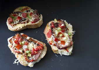 Three gourmet bruschetta made of bacon, tomatoes and cheese 