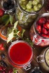 Berries jam in glass jar and wood background