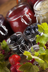 Berries jam in glass jar and wood background