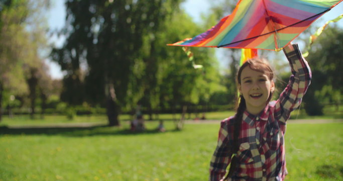 Cheerful girl running with a colorful kite in her hand 