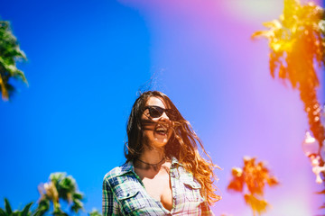 portrait of beautiful young girl in sunglasses in palm trees in summer in sunglasses smiling wide in Barcelona  - 90826121