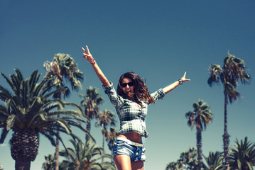 Beautiful funny smiling young girl is jumping in palm trees in sunny Barcelona in summer - 90826189