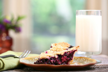 Slice of Blueberry Pie with milk on rustic wooden table