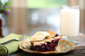 Slice of Blueberry Pie with vanilla ice cream on rustic wooden table