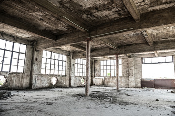 Empty industrial loft in an architectural background with bare cement walls, floors and pillars supporting a mezzanine