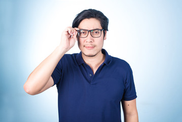Handsome Asian man looking up while holding glasses with hand, o