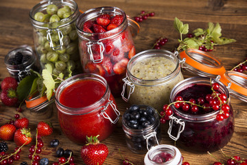 Glass of mixed berry jam with strawberries, bilberries, red currants and blackberries