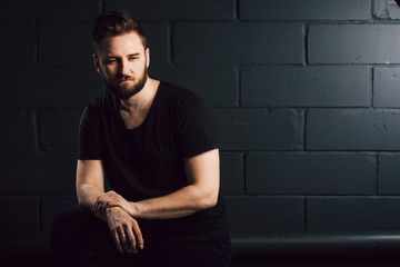 Obraz premium attractive men with beard in black shirt having problems in his life near brick wall