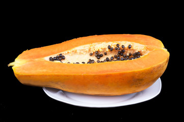 Cutted ripe papaya on black background.
