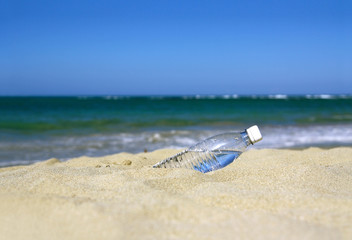 Fototapeta na wymiar Plastic bottle of water in sand on tropical sandy beach