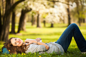 Young woman using her tablet computer while relaxing outdoors