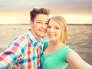 Fototapeta na wymiar smiling couple with smartphone on summer beach