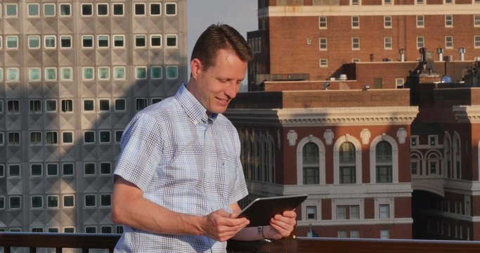Man Uses Tablet PC on Rooftop Deck in Pittsburgh