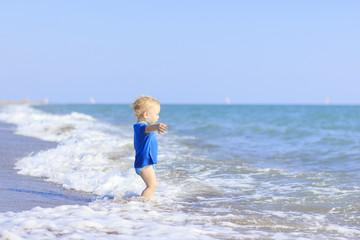 baby playing on the waves of the sea. baby delighted: he first sees the sea and the bold move to play in the waves