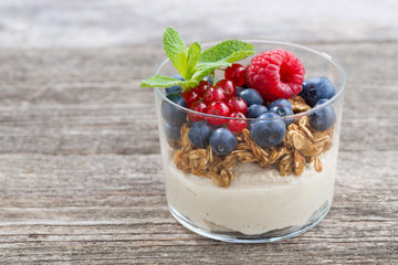 dessert with milk cream, muesli and berries on wooden table