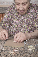 a senior woman peeling garlic in kitchen
