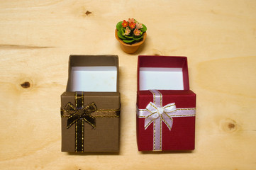Red and brown gift boxes with little flower on wooden background