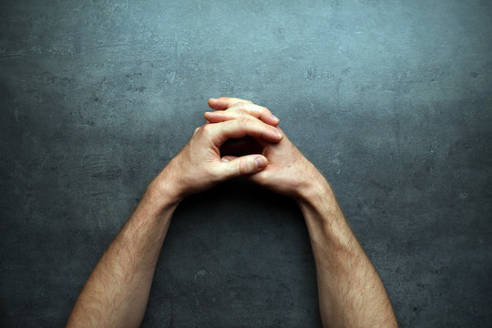 Pray, man hands on grey table background