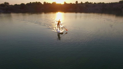 Aerial: young girl boarding SUP