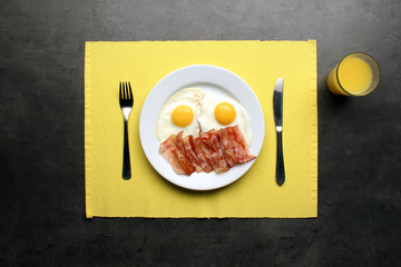 Fried eggs with bacon on kitchen table, top view