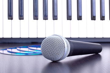 Microphone, cd disks and piano keyboard on black table