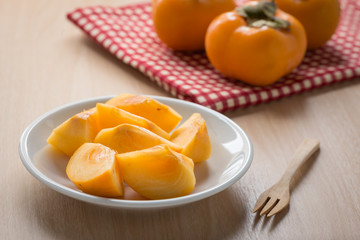 Naklejka na ściany i meble Cut fruit, fresh persimmon on dish.