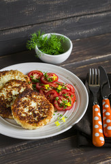 delicious vegetarian cabbage cutlets and fresh tomatoes on a light plate  on a dark wooden surface