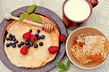 Pancakes  with raspberries, blueberries, milk, honeycomb. top view