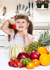 little cute girl holding and eating a strawberry in the kitchen
